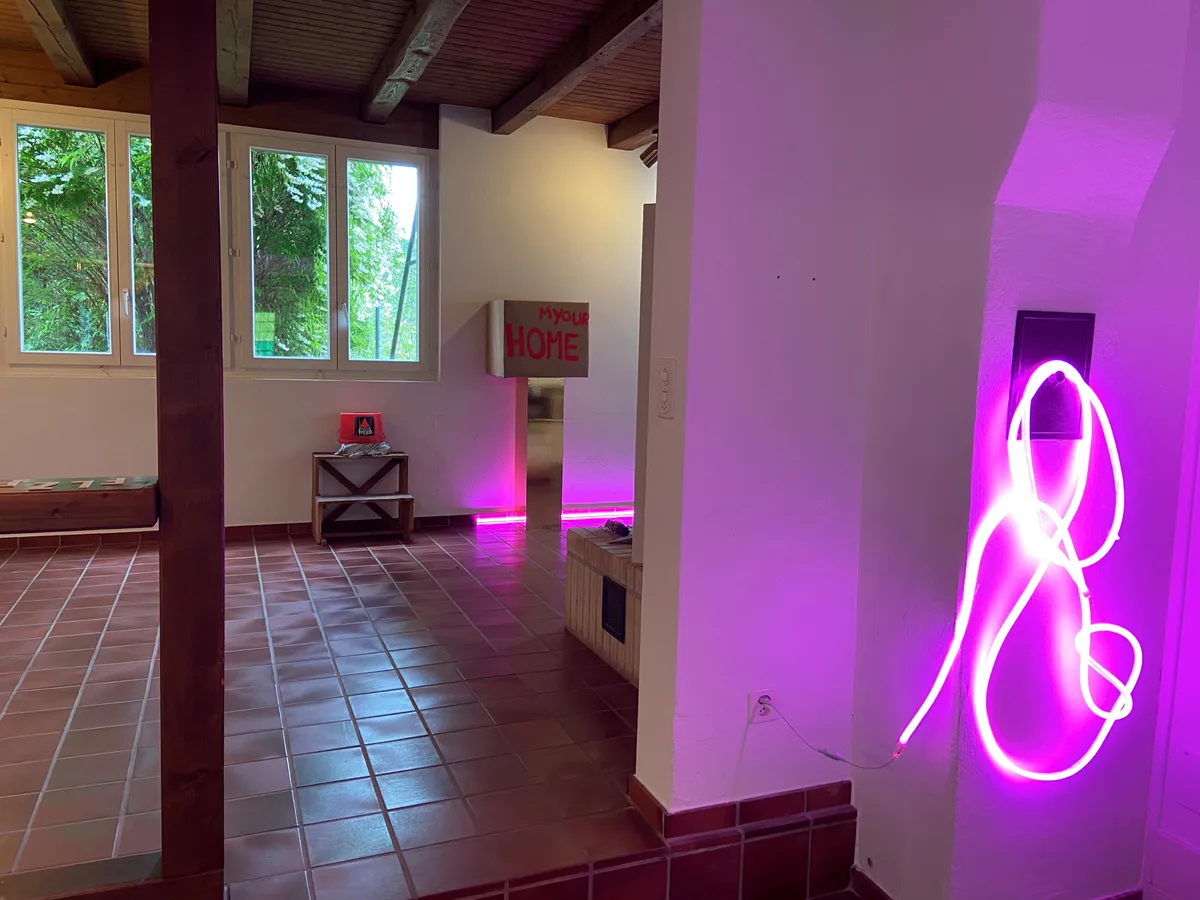 Vorne eine pinke Lichterkette, hinten eine Schachtel auf einem goldenen Sockel.